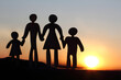 unrecognizable silhouettes of a man and a woman with children holding hands together against the backdrop of a sunset. with hope for a bright future