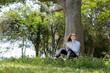 © Buonaventura - Young woman using a smartphone at day time with a green park in the background. High quality photo