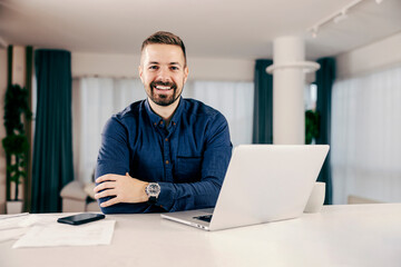 Wall Mural - a happy businessman working online from his cozy home and smiling at the camera.