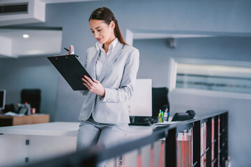 A businesswoman checking on paperwork at modern office.