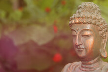 Buddha Statue In Garden With Blurred Flowers In Background
