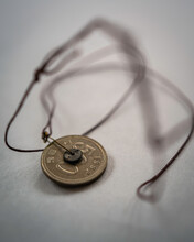 A Homemade Korean Coin Necklace With Characters Of 500 And 1992, Literally Meaning Five Hundred Pennies Minted In 1992, Tied To Circular Strings On The White Background