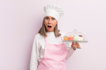 Wall Mural - middle age woman looking very shocked or surprised. baker and cakes concept