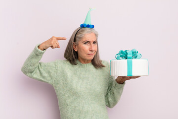 Wall Mural - middle age woman feeling confused and puzzled, showing you are insane. bitrthday cake concept