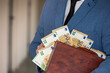 young boss businessman in expensive suit with tie holds bag with euro banknotes.