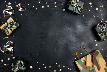 Wall Mural - Frame of camouflage hearts, gifts, bag and stars on black background.