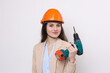 © Mountains Hunter - Girl engineer in an orange construction helmet with a screwdriver and a hammer on a white background.