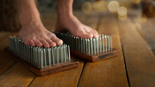 Male Bare Feet Stand On A Sadhu Boards With Sharp Nails On Wooden Floor Indoor, Close Up, Selected Focus.