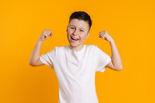 Brunette white boy in t-shirt smiling and making winner gesture