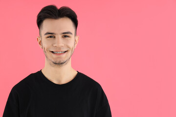 Attractive young man in t-shirt on pink background