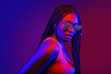 portrait of fashion young girl in cool sunglasses in red and blue neon light in the studio