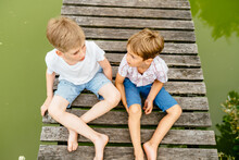 Summer Adventure Friendship Childhood Concept. Two Children Boy Talking Secret Plans Or Ideas On Wooden Bridge By Lake In Summer.