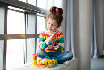 a little girl sculpts from plasticine.