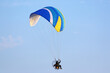 Paramotor pilot flying in a blue sky