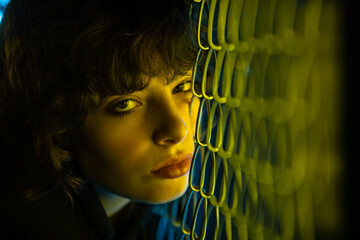 Wall Mural - Portrait of a young woman with curly hair in yellow neon lighting.