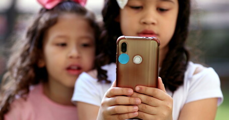 Little girls staring at cellphone screen. children on social media