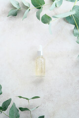 Wall Mural - transparent dropper bottle with serum lotion or essential oil on stone table with eucalyptus leaves.