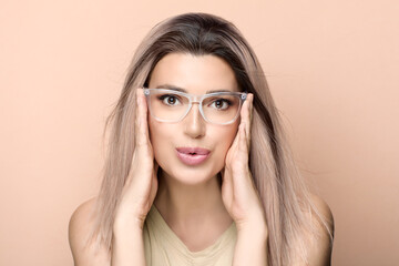 Wall Mural - happy woman in glasses looking at camera against beige background