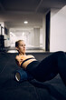Athletic woman with physical disability uses foam roller while warming up for sports training at gym.