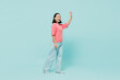 © ViDi Studio - Full size side view young smiling happy woman of Asian ethnicity 20s wearing pink sweater walk going waving hand isolated on pastel plain light blue color background studio. People lifestyle concept.