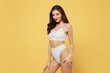 Seductive stunning confident sexy lovely attractive young brunette woman 20s in white underwear with perfect fit body standing posing look camera isolated on plain yellow background studio portrait.