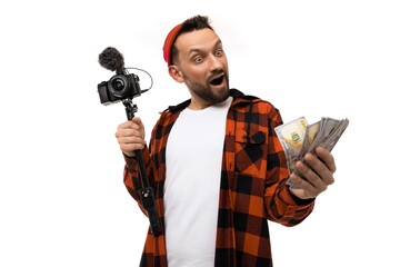 young male blogger with a video camera with a microphone and money in his hands on a white background