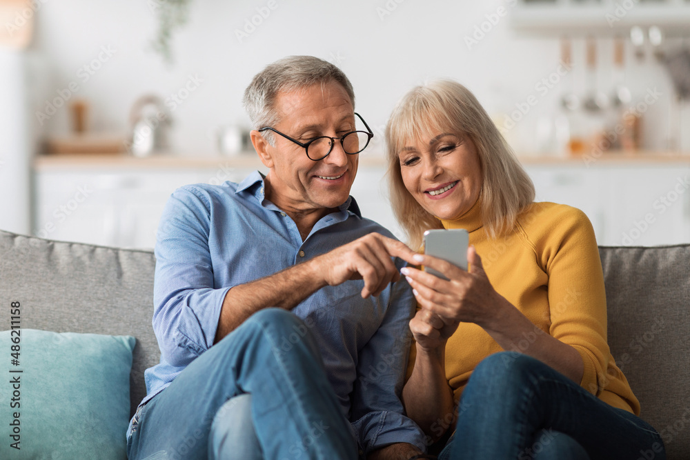 Older Spouses Using Mobile Phone Sitting On Sofa At Home Stock Photo ...