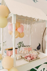 Beautiful candy bar decor with homemade craft marshmallows and cupcakes in a wooden white cart