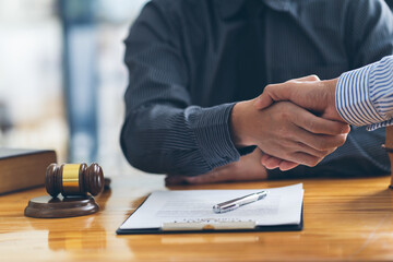 Handshake after good cooperation, Businesswoman Shaking hands with Professional male lawyer after discussing good deal of contract in courtroom, Concepts of law, Judge gavel with scales of justice.