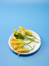 Fresh Zucchini Flowers In The Plate On A Blue Background