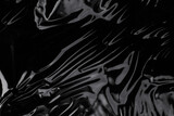 Fototapeta Kosmos - Wrinkled plastic wrap texture on a black background. Cellophane package wallpaper