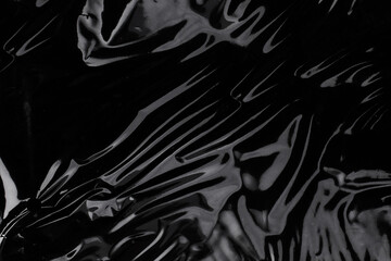 wrinkled plastic wrap texture on a black background. cellophane package wallpaper