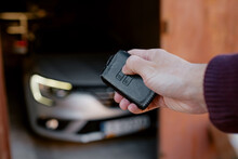 Close-up of a man's hand locking or unlocking a car with keyless in garage. Black leather case for keyless