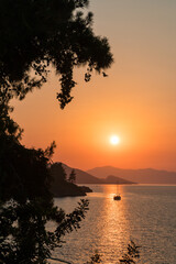 Wall Mural - calm sea and sunset. sun is setting behind the hills on the horizont. beautiful nature background.
