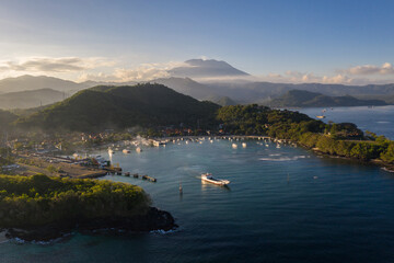 Wall Mural - Dramatic view of a boat leaving the Padang Bai harbor in eastern Bali with the Agung volcano in the background at sunset in Indonesia