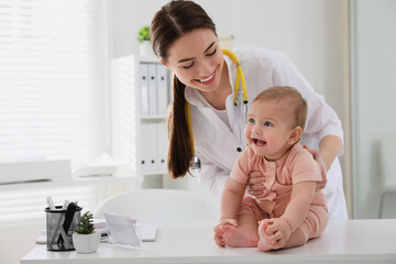 young pediatrician examining cute little baby in clinic