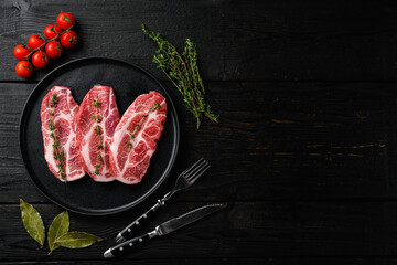 Wall Mural - Piece of fresh raw pork from the neck, with ingredients, on black wooden table background, top view flat lay, with copy space for text