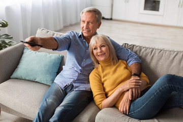 Wall Mural - Happy Senior Spouses Watching TV Relaxing At Home