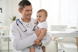 © New Africa - Pediatrician with cute little baby in clinic. Space for text