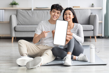 Aufkleber - Athletic asian couple exercising from home, showing smartphone, mockup