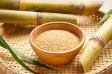 Brown sugar and sugarcane in a wooden tray. Close-up.