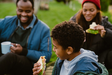 Wall Mural - Black family laughing during picnic on blanket at backyard