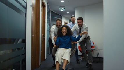 Wall Mural - Business group racing chair having fun party in diverse office workplace hallway