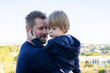 © Danko - Happy dad holding his son, little funny kid boy on arm, walking together in a park in spring, autumn or winter. Happy, joyful family.