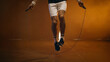 Cropped view of athletic sportsman jumping with rope on dark background