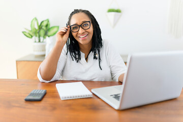 black woman using computer in modern kitchen interior