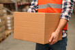 © New Africa - Worker with cardboard box in warehouse, closeup. Wholesaling