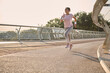 © Taras Grebinets - Determined strong athletic middle aged African American sportswoman in sportswear during her morning run, running on a treadmill along a city bridge with beautiful nature in the background