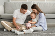 © Prostock-studio - Family Budget. Happy Parents Looking At Infant Son Putting Coins To Piggybank