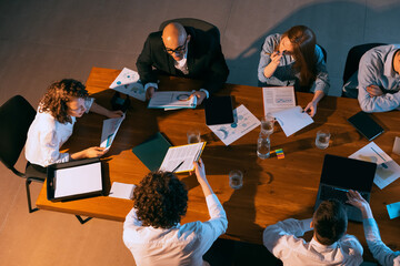 Aerial view of young multiethnic people talking, working with colleagues, co-workers at office, indoors. Work, finance, tech concept.